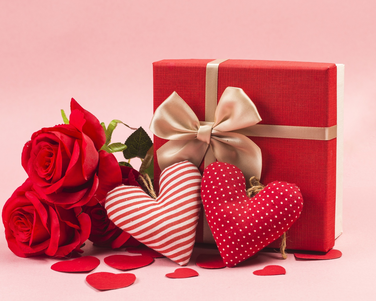 Три красные розы с сердечками и подарком на розовом фоне