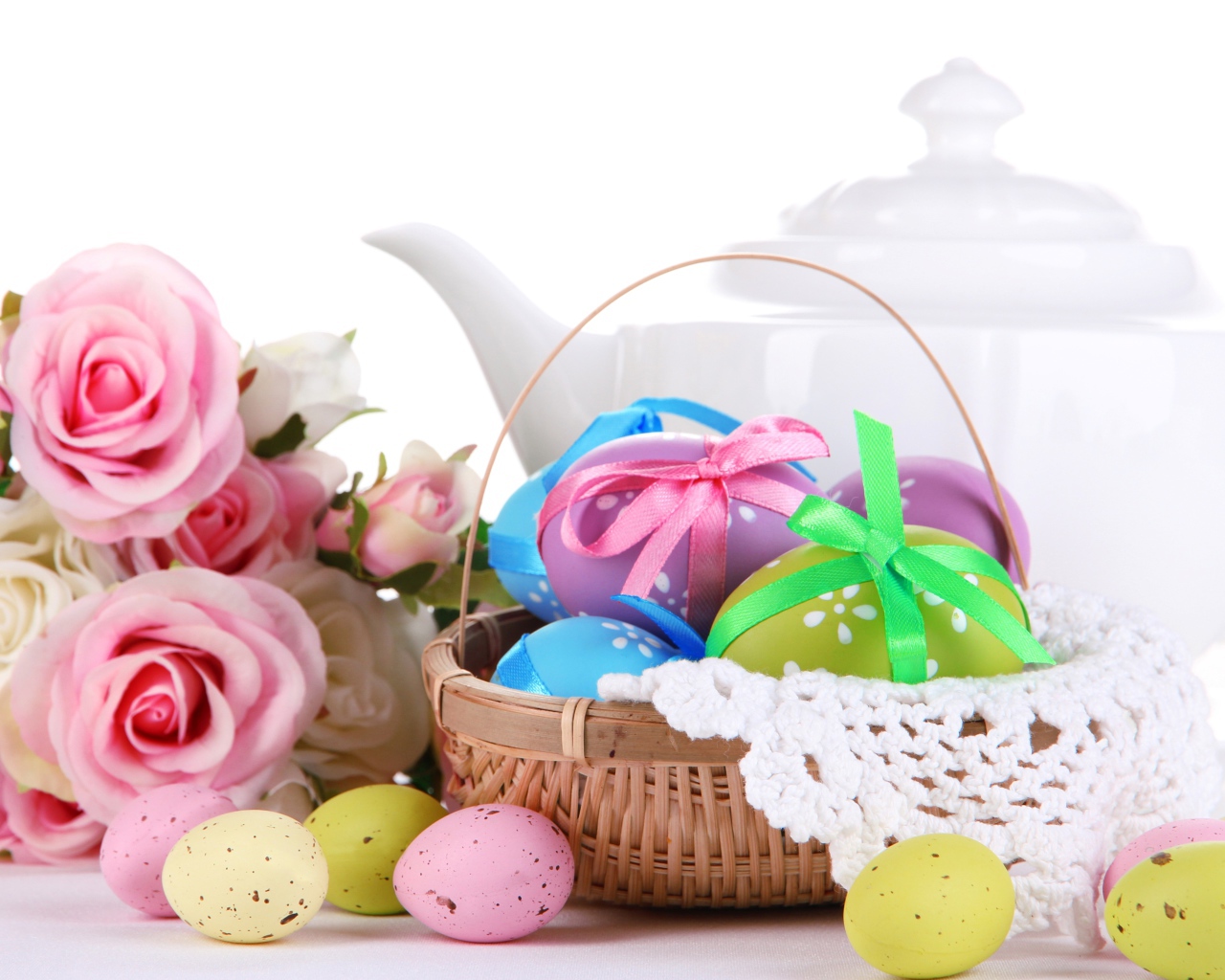Корзина с пасхальными яйцами на столе с букетом роз и белым чайником