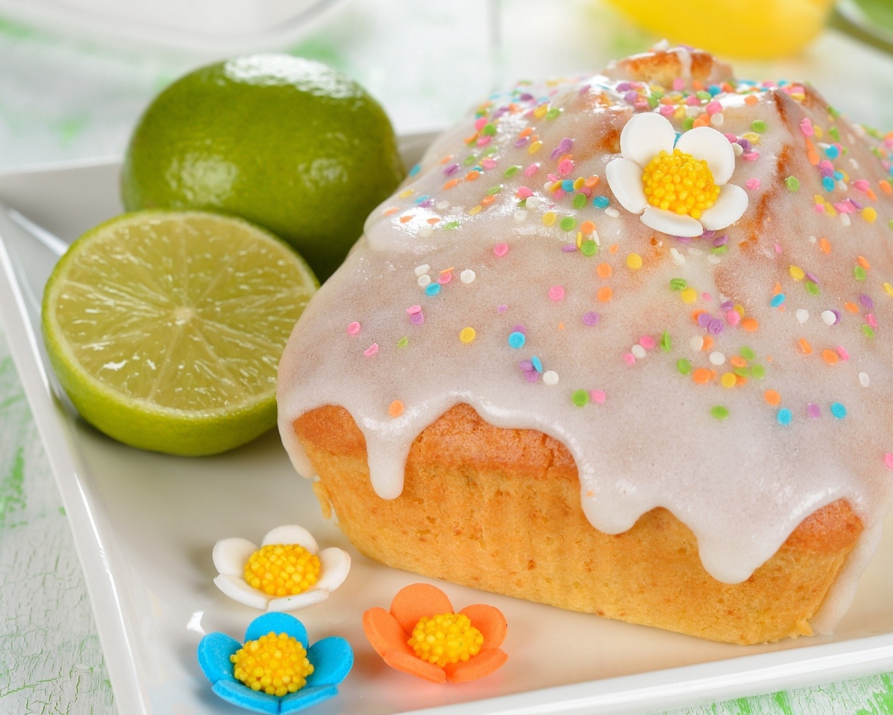 Красивый пасхальный кулич на белой тарелке с лаймом и сахарными цветами