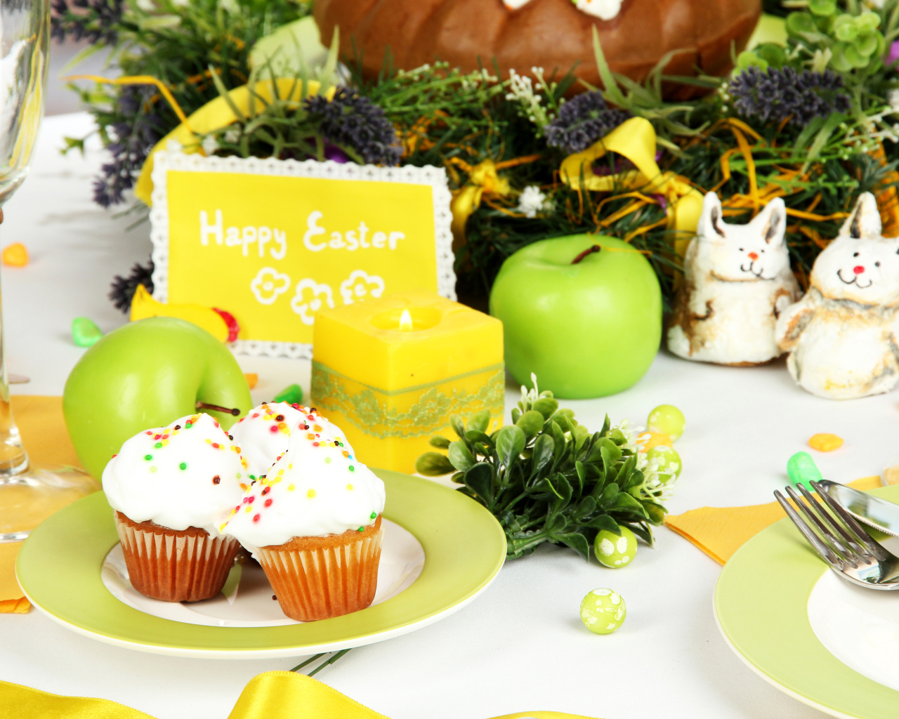 Накрытый пасхальный стол с кексами и зажженной свечой 