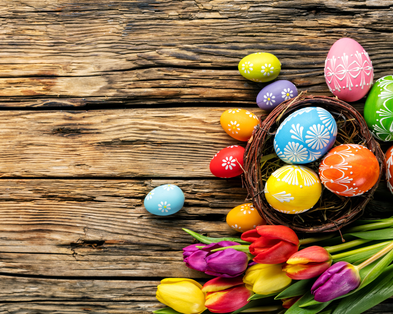 Крашеные пасхальные яйца с букетом тюльпанов на деревянном фоне