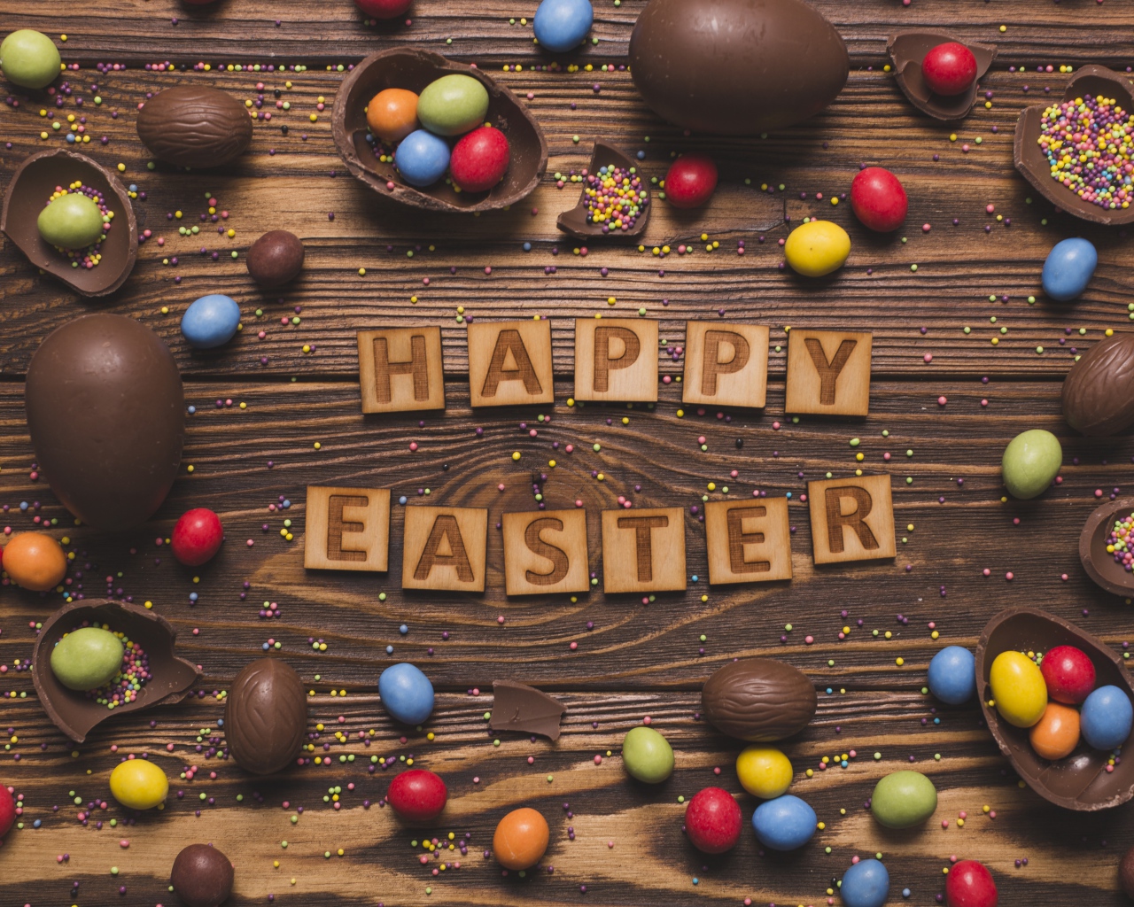 Надпись на английском Счастливой Пасхи на столе с шоколадными яйцами и конфетами