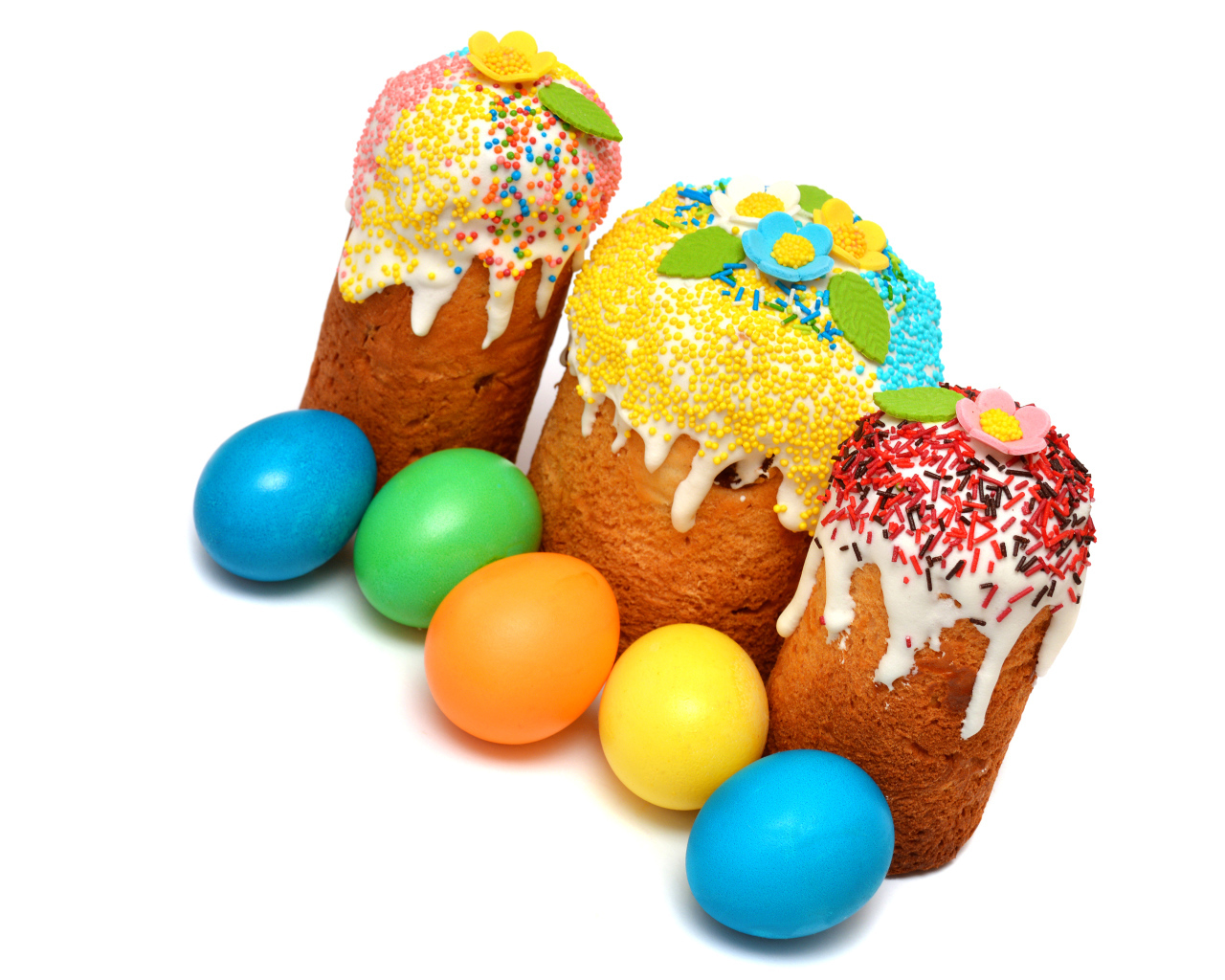 Три кулича с крашеными яйцами на белом фоне к празднику Пасха