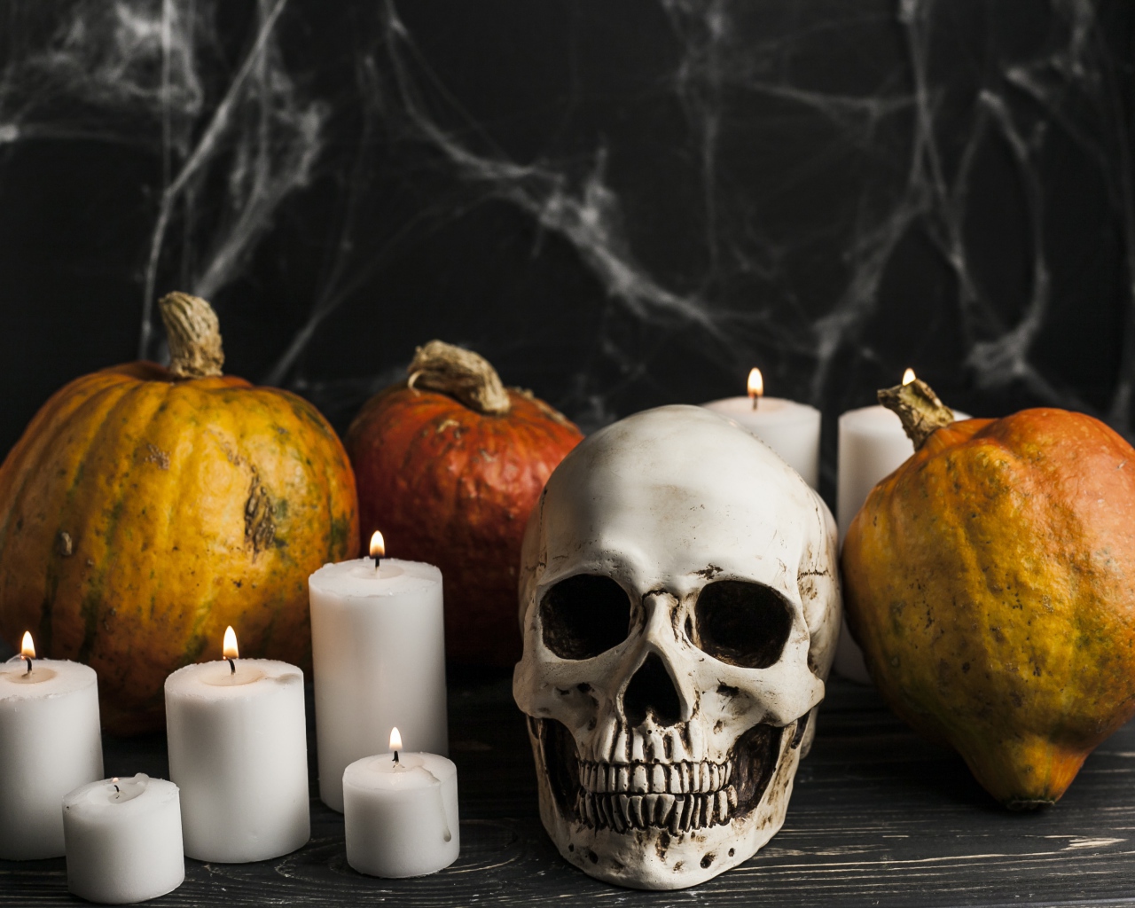 Череп, свечи и тыквы на столе с паутиной