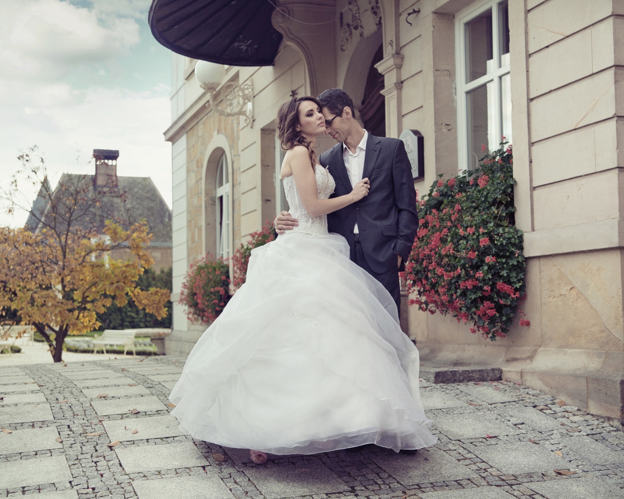 Жених и невеста стоят у здания 