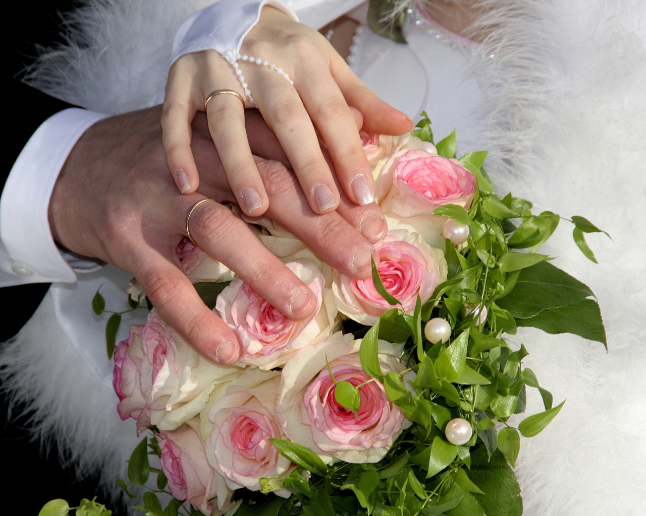 Руки жениха и невесты на букете с розовыми розами