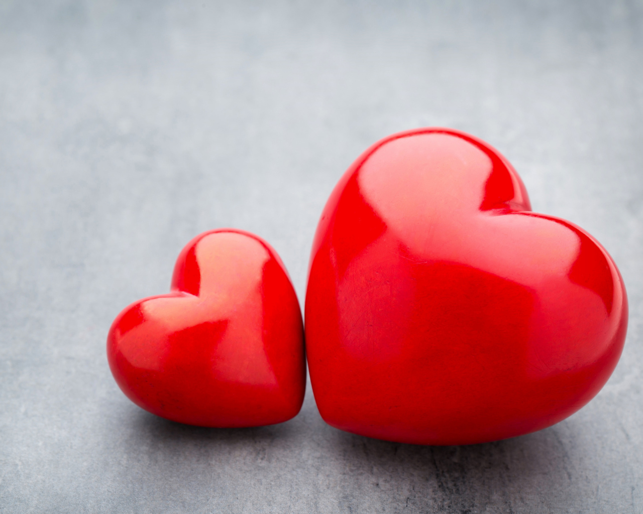 Большое и маленькое красное сердце на сером столе