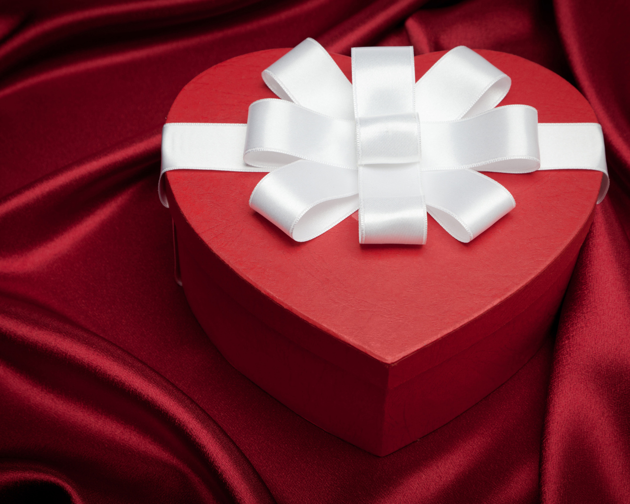 Большая красивая красная коробка в форме сердца с белым бантом