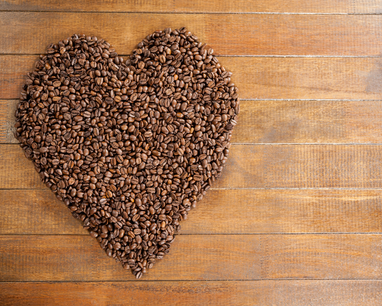 Большое сердце из кофейных зерен на деревянном столе