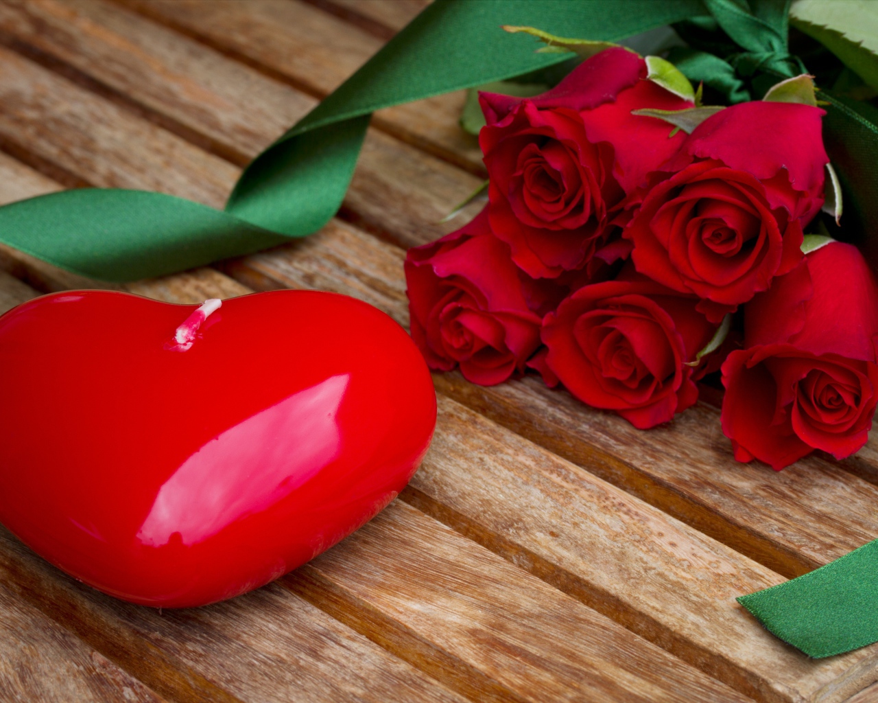 Большое сердце на деревянном столе с букетом красных роз 