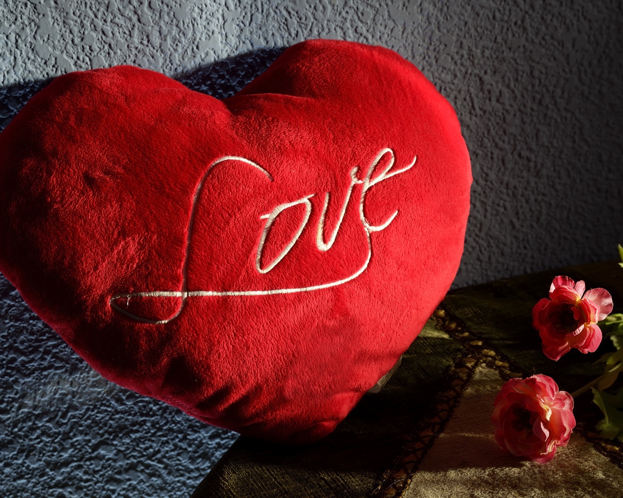 Большое плюшевое красное сердце у стены 