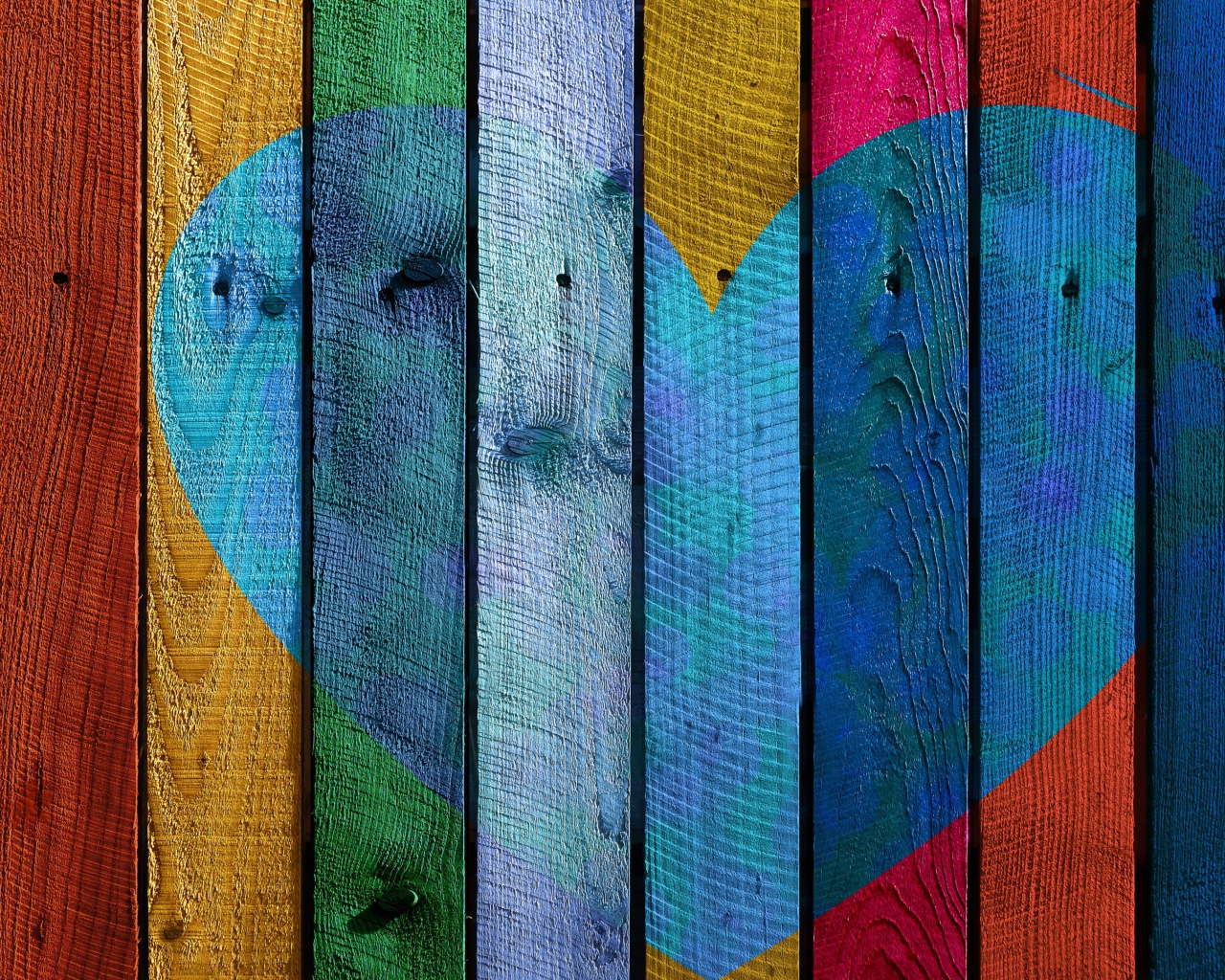 Голубое сердце нарисовано на разноцветном заборе