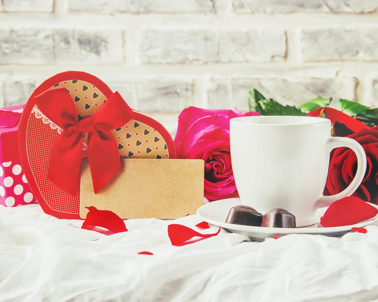 Коробка с подарком на столе с чашкой кофе и красными розами 