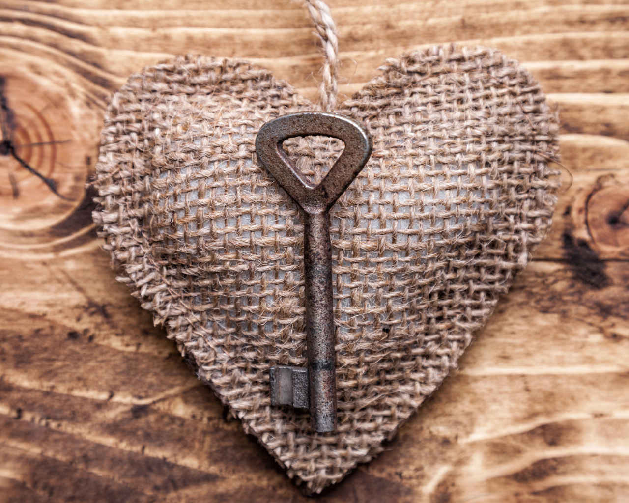 Сердечко из мешковины с ключом на деревянном фоне