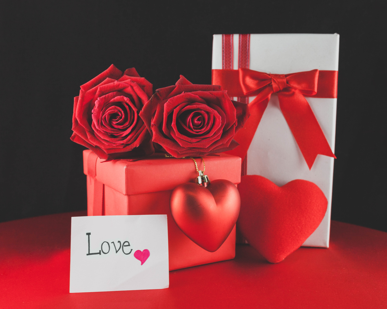 Коробки с подарками на столе с красными розами и сердцем