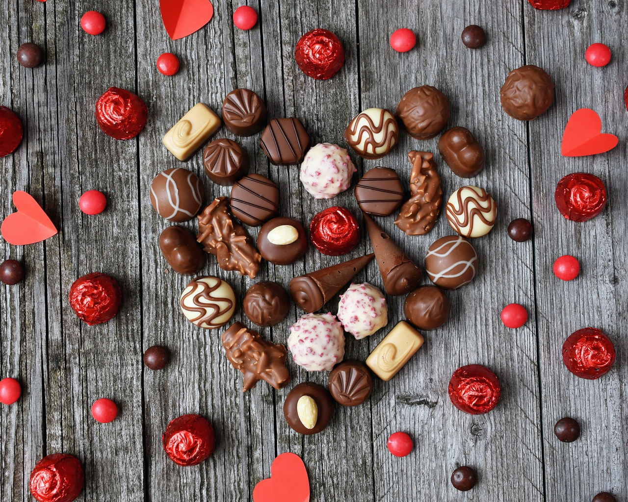 Сердце из шоколадных конфет ассорти на деревянном столе для любимой 