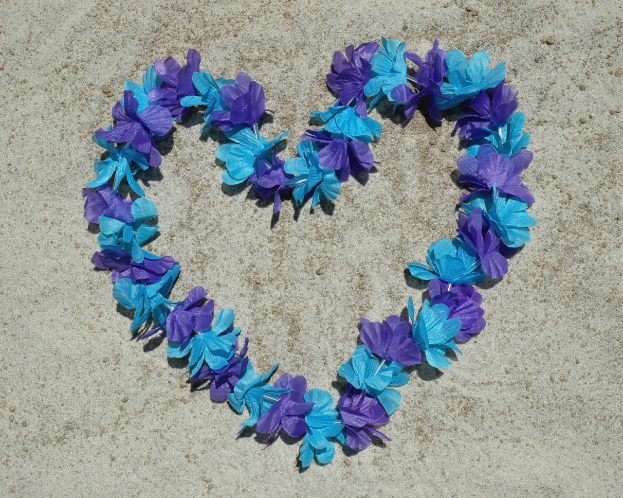 Сердце из цветов на песке на пляже