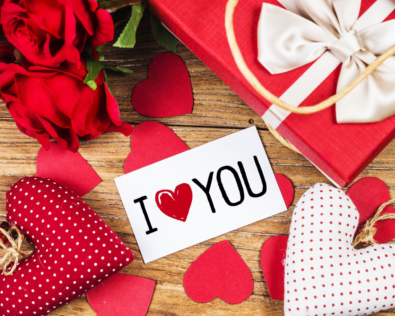 Сердечки, цветы и подарок на столе с запиской