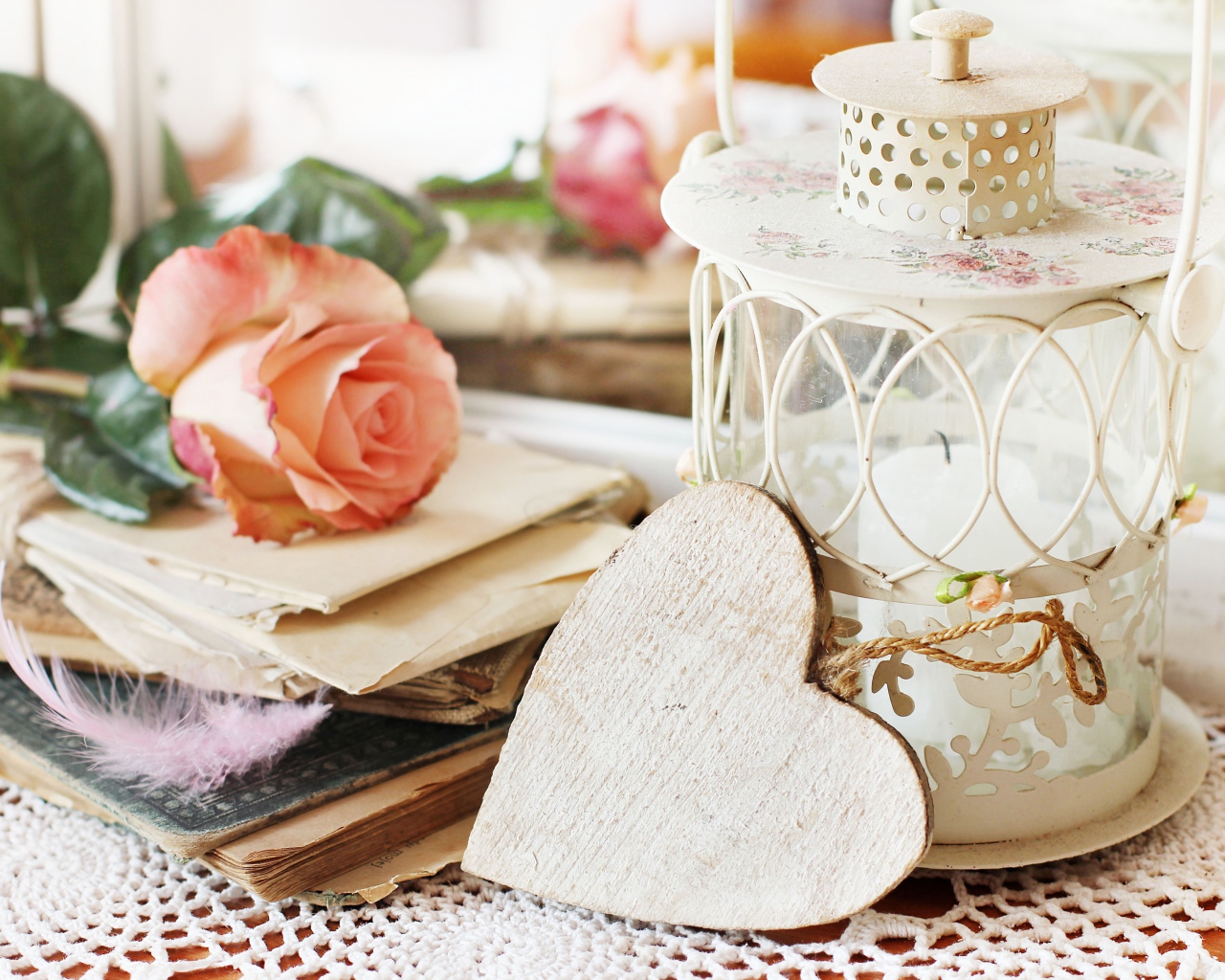 Фонарь со свечей на столе с розой, сердцем и книгами