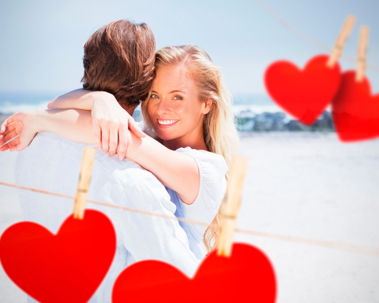 Влюбленная пара на берегу моря с красными сердечками