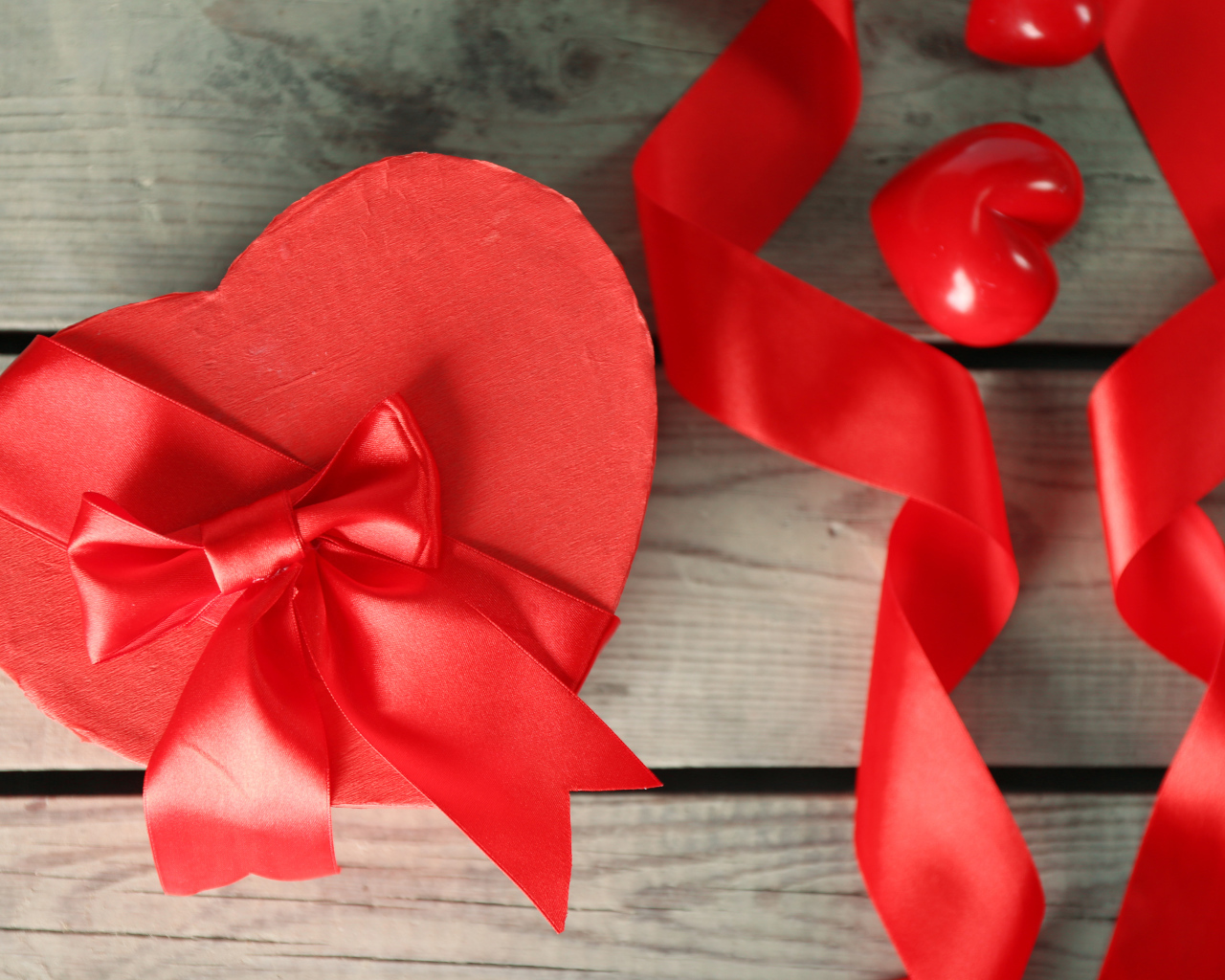 Красная коробка в форме сердца на деревянном столе с красными лентами
