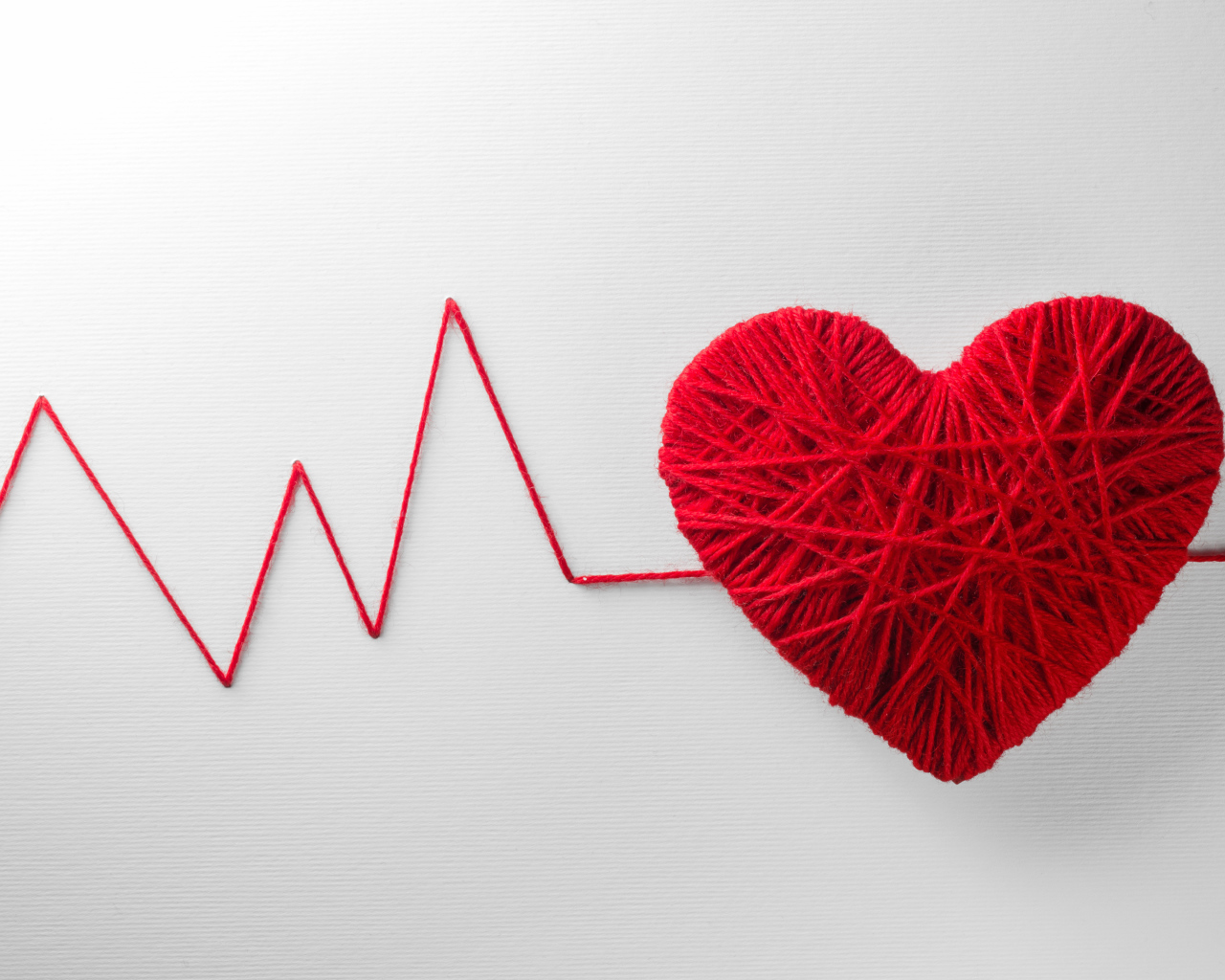 Красное сердце из нитей на сером фоне 