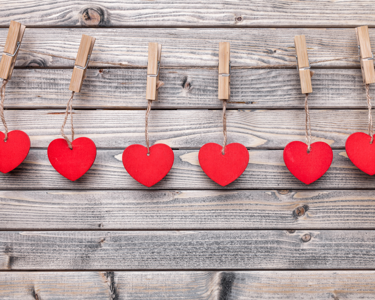 Красные сердечки на прищепках на деревянном столе 