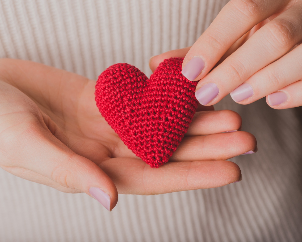 Красное вязаное сердце в руках у девушки