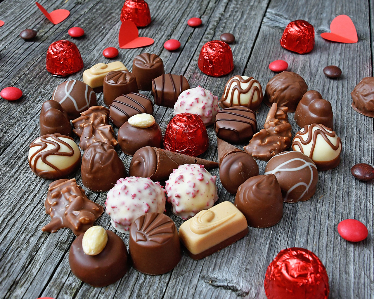 Сладкое сердце из шоколадных конфет на деревянном столе