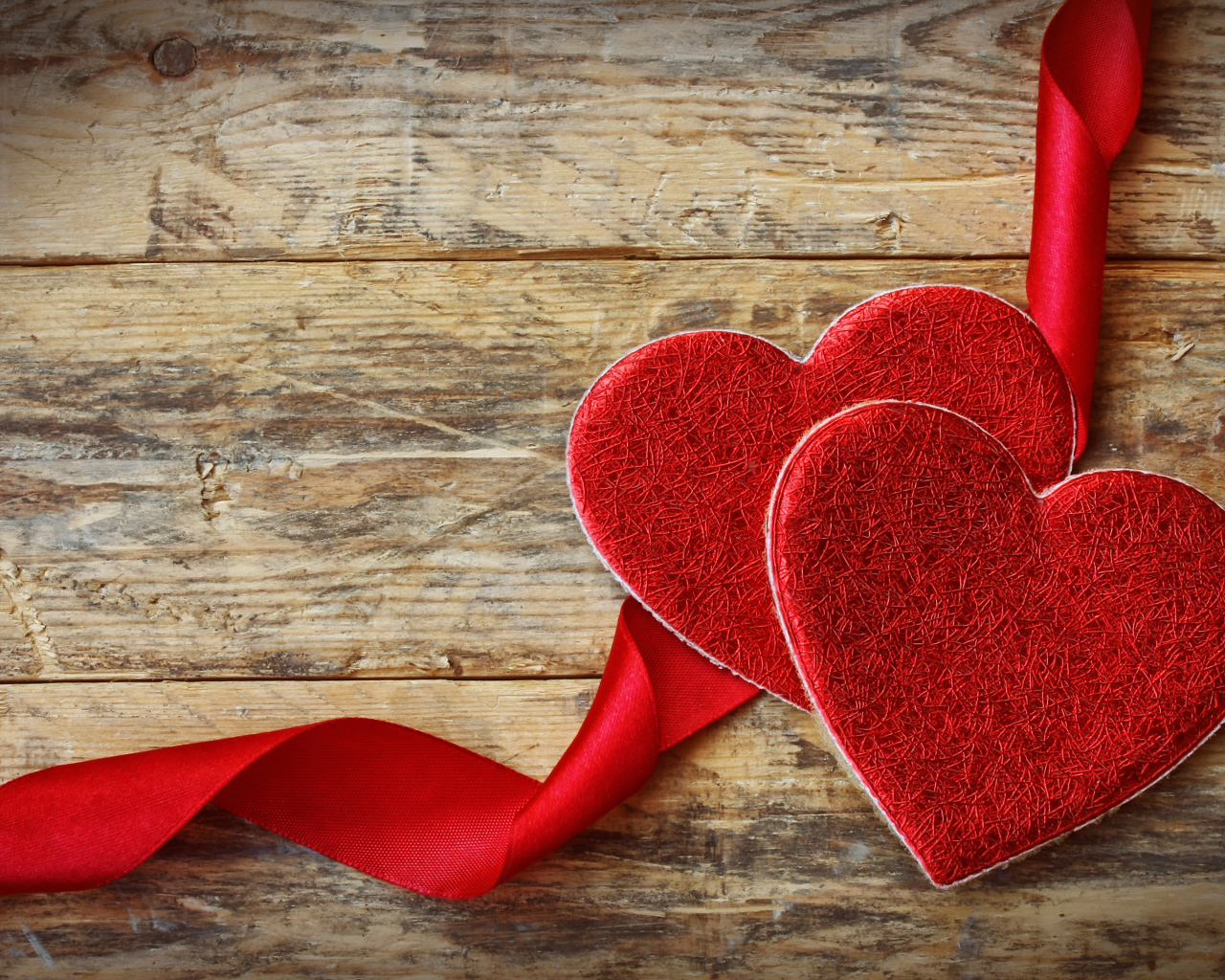 Два сердца с красной лентой на деревянном столе
