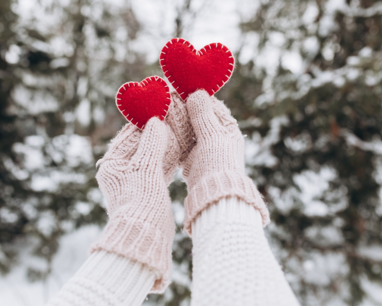 Два красных сердечка из ткани в руках у девушки 