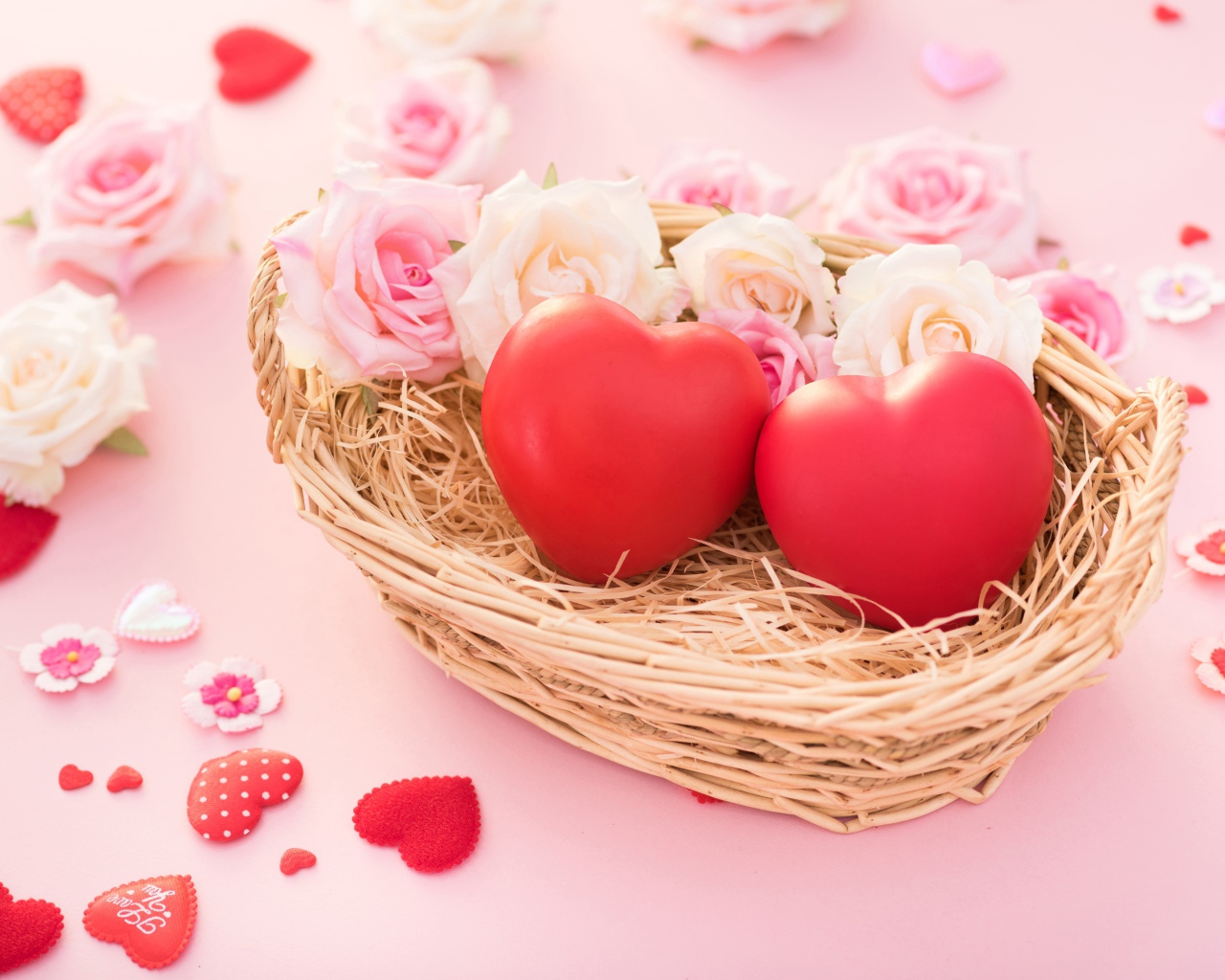 Два красных сердца лежат в корзинке с розами 
