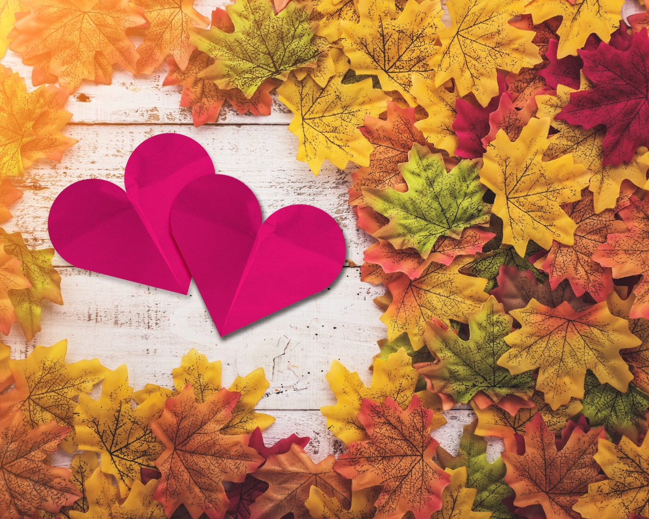 Два красных сердца на столе с желтыми листьями