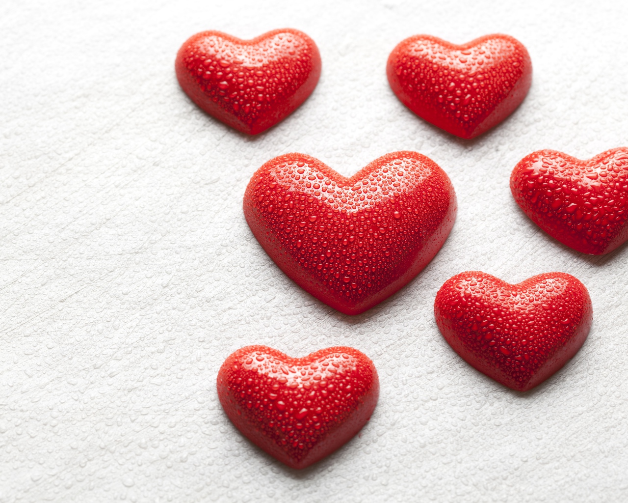 Мокрые красные сердечки на белой поверхности 