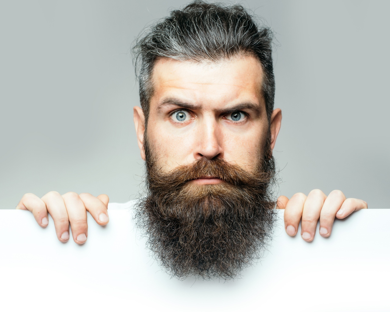 Голубоглазый мужчина с бородой на сером фоне