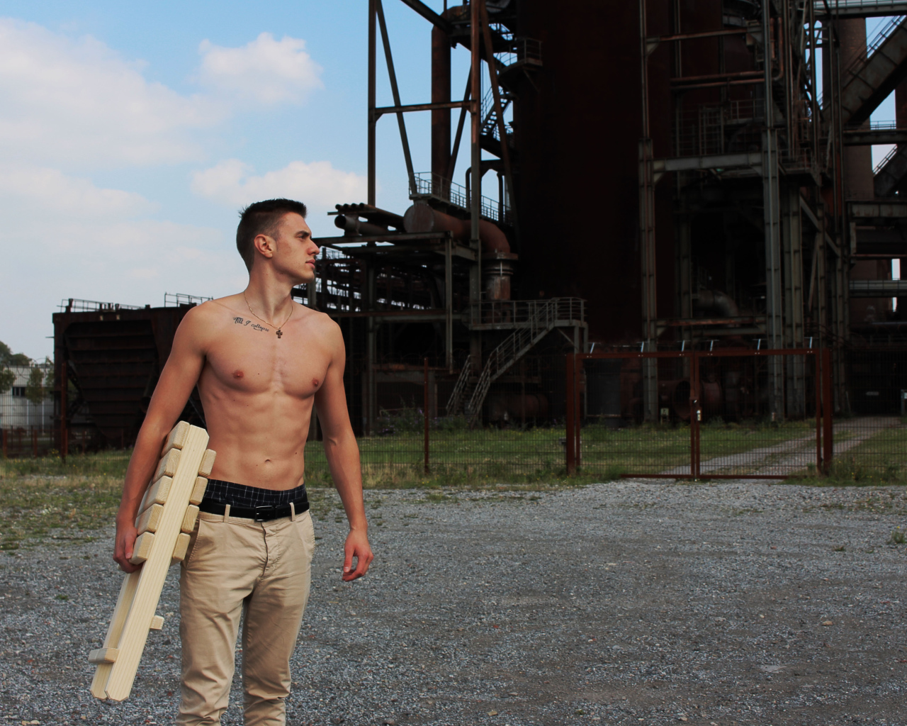 Красивый молодой парень стоит на фоне завода