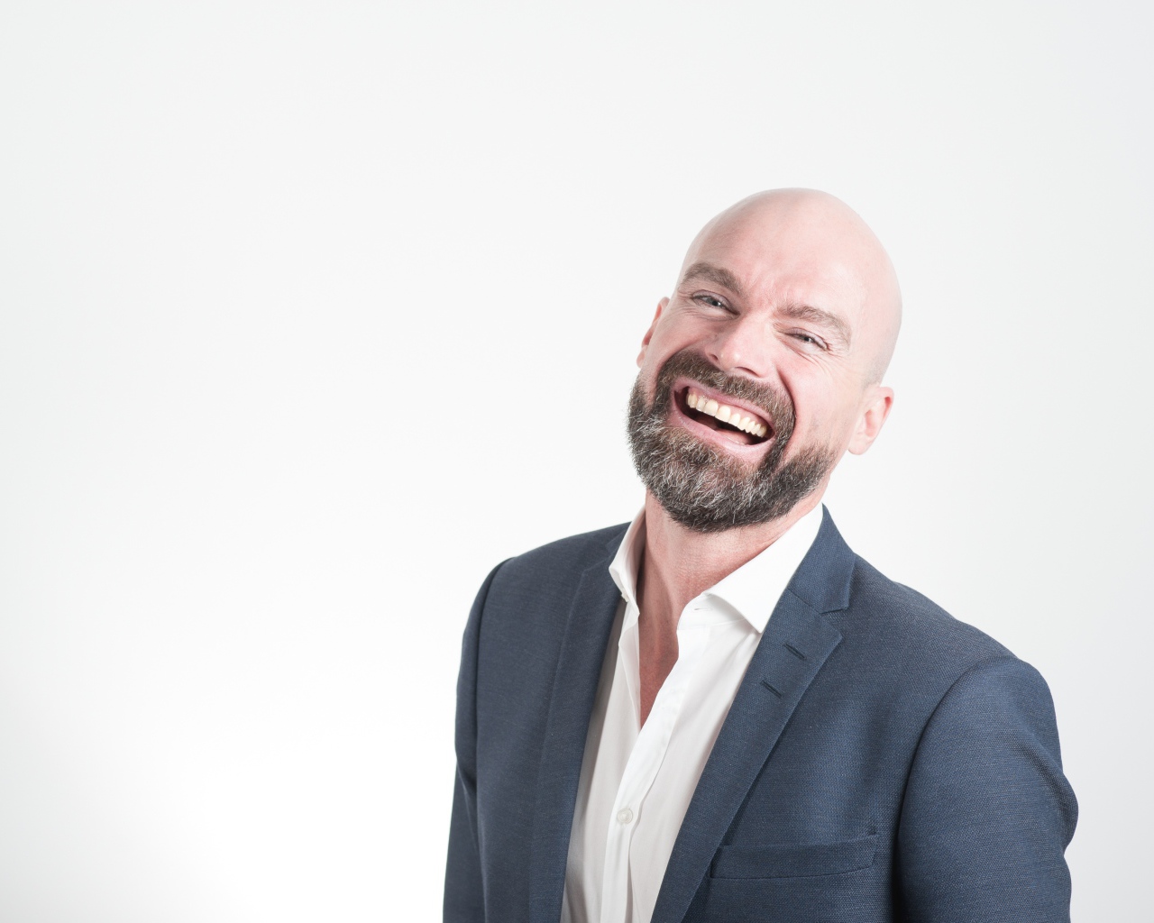 Смеющийся мужчина с бородой в костюме на сером фоне