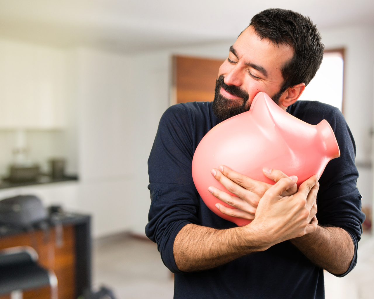 Мужчина обнимает розовую свинью копилку 