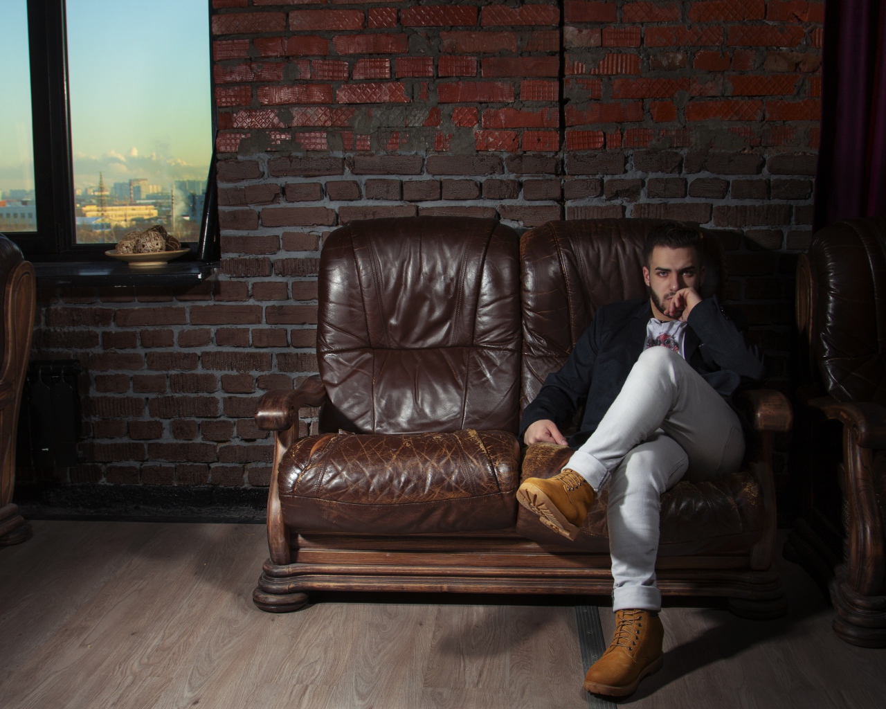 Стильный мужчина сидит в кожаном кресле 