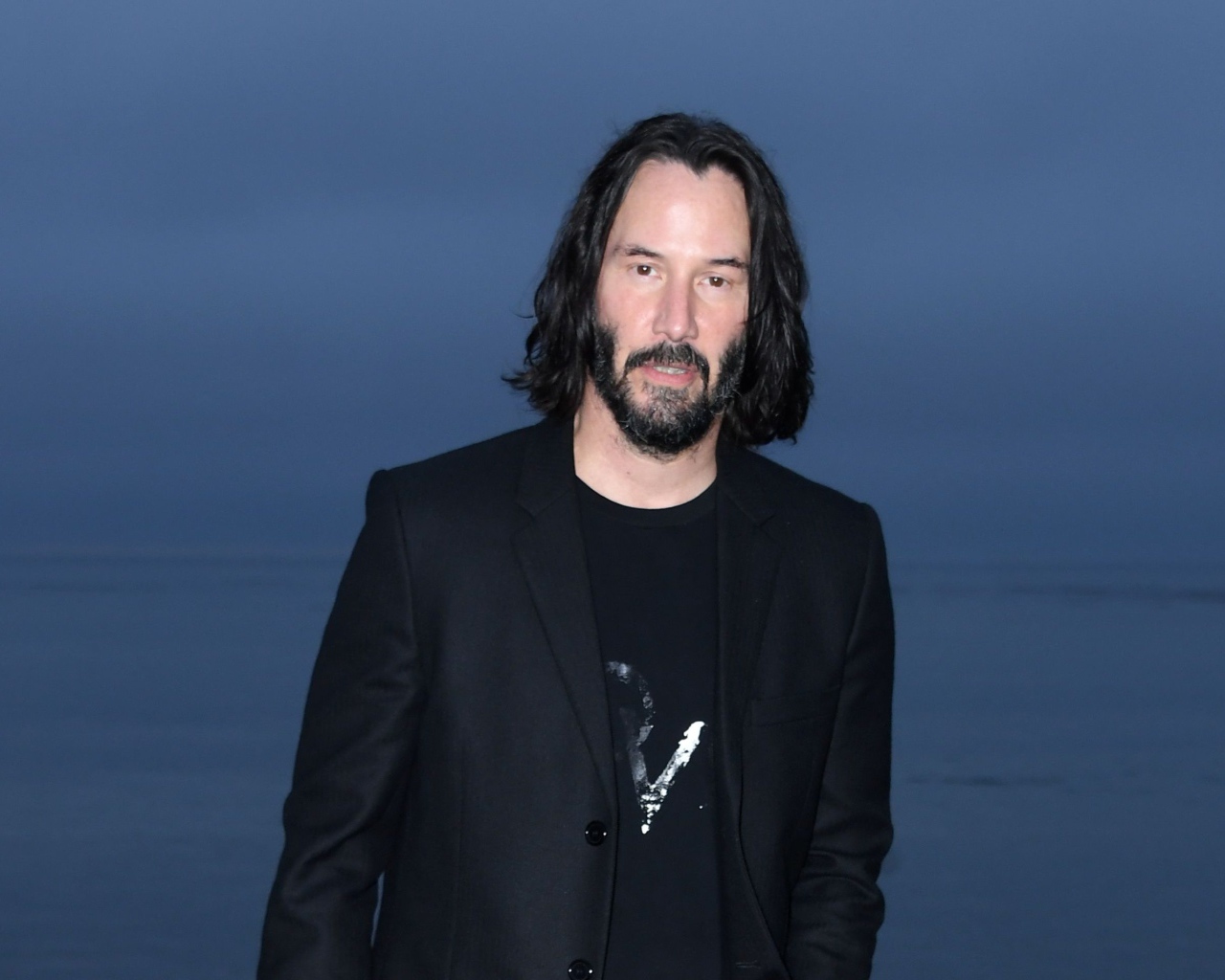 Актер Киану Ривз с бородой на синем фоне