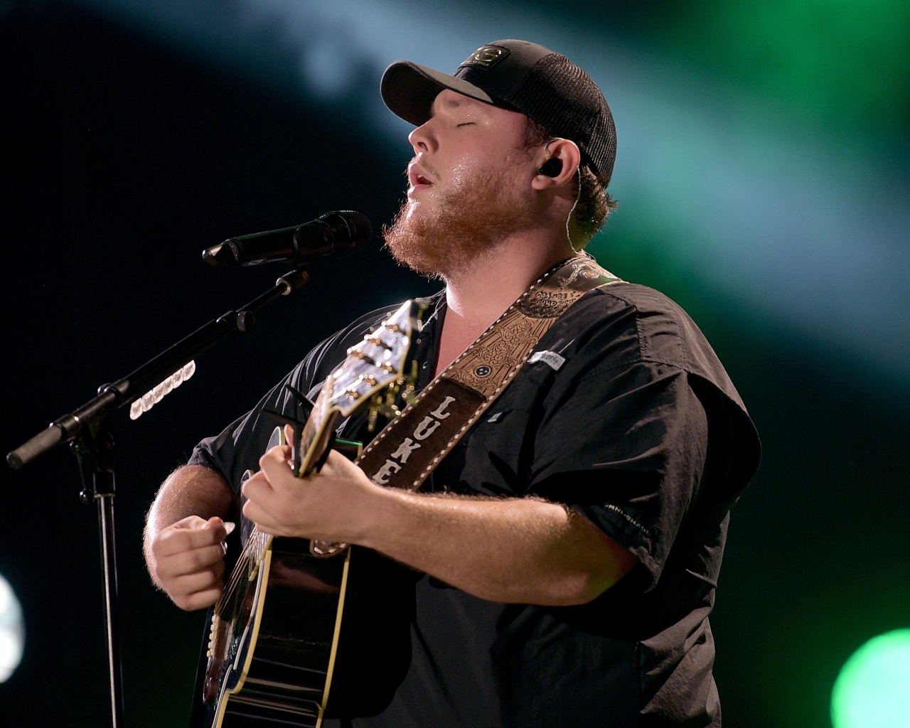 Кантри исполнитель Люк Комбс с гитарой поет на сцене