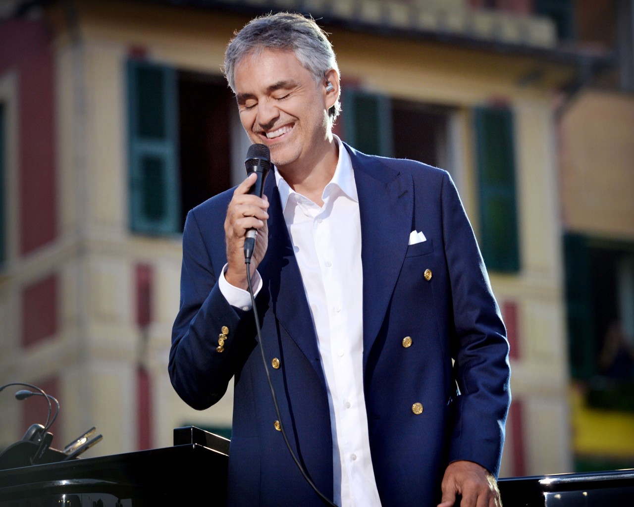 Итальянский певец Андреа Бочелли в костюме с микрофоном