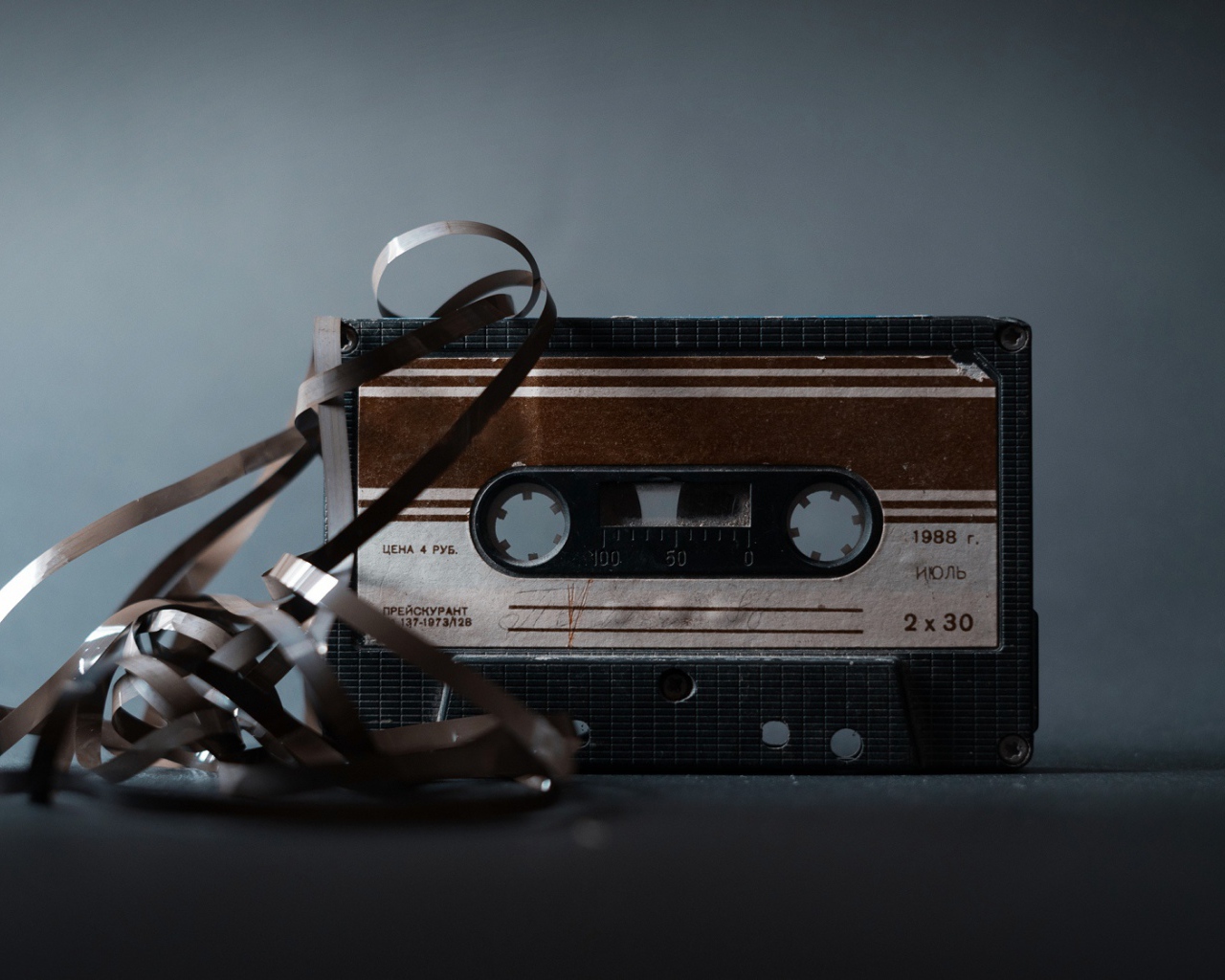 Старая кассета с вытянутой пленкой на сером фоне 