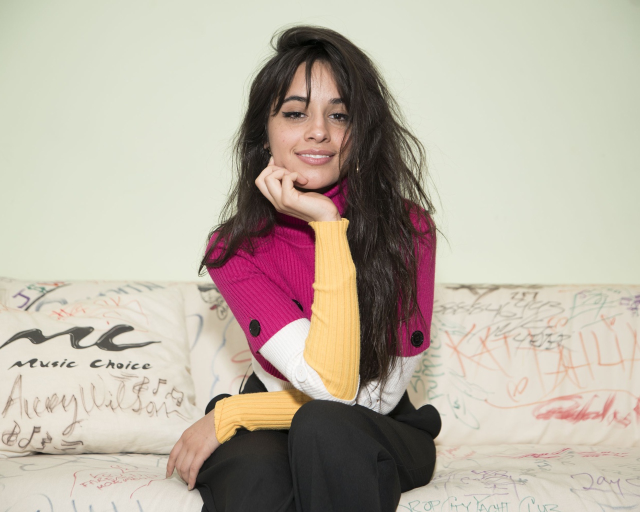 Улыбающаяся Камила Кабельо сидит на диване