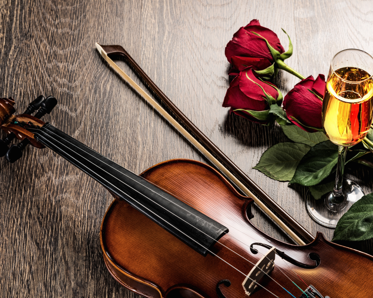 Скрипка лежит на столе с бокалом шампанского и красными розами