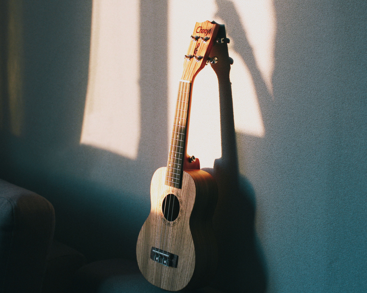 Желтая гитара стоит у серой стены