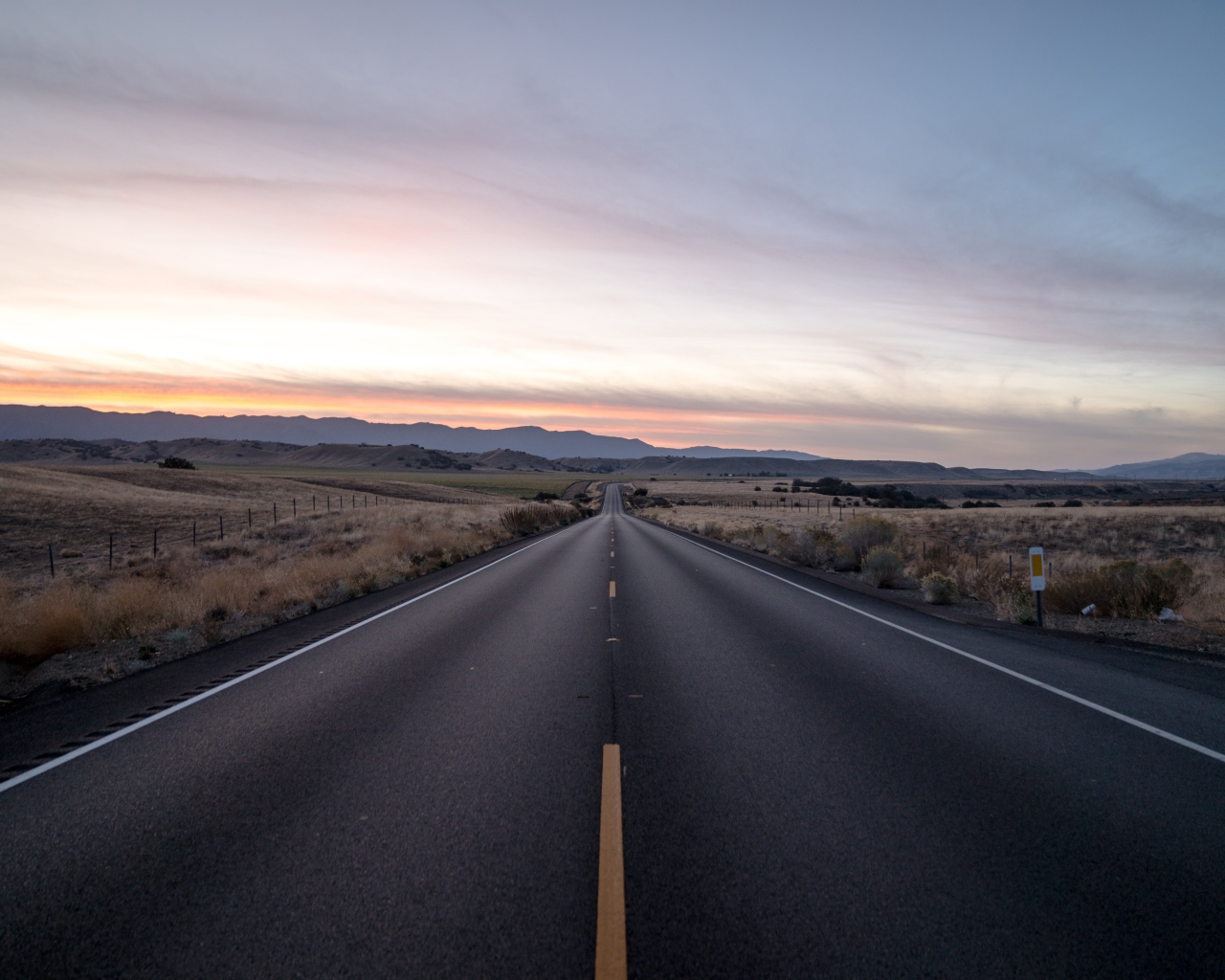 Асфальтная дорога уходит вдаль на фоне неба