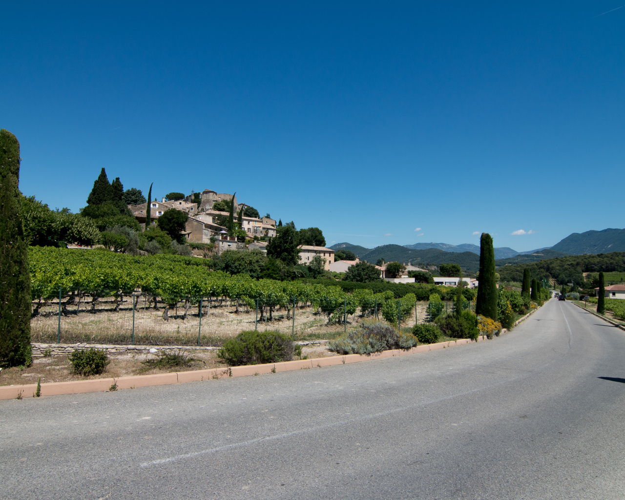 Асфальтовая дорога у большого дома под голубым небом