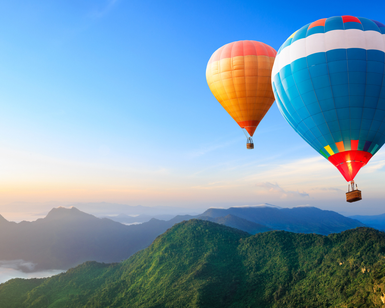 Большие воздушные шары в голубом небе над зелеными холмами