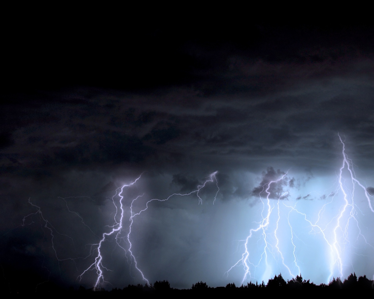 Яркие молнии в черном грозовом небе ночью